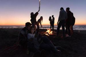 paar genieten van vreugdevuur met vrienden Aan strand foto