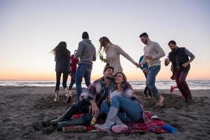 paar genieten van met vrienden Bij zonsondergang Aan de strand foto