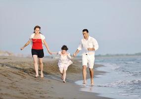 gelukkig jong familie hebben pret Aan strand foto