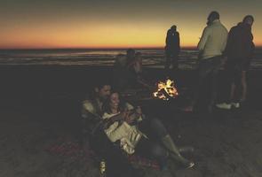 paar genieten van vreugdevuur met vrienden Aan strand foto