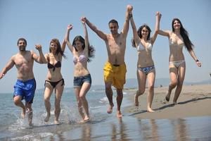 gelukkig mensen groep hebben pret en rennen Aan strand foto