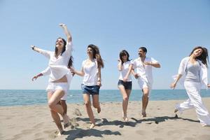 gelukkig mensen groep hebben pret en rennen Aan strand foto