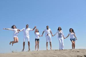 gelukkig mensen groep hebben pret en rennen Aan strand foto