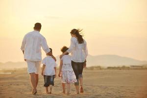 gelukkig jong familie hebben pret Aan strand Bij zonsondergang foto