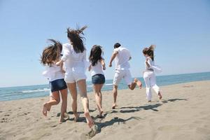 gelukkig mensen groep hebben pret en rennen Aan strand foto