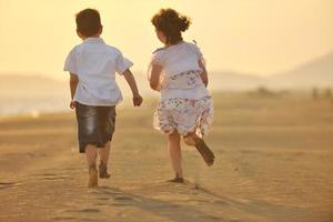 gelukkig jong familie hebben pret Aan strand Bij zonsondergang foto