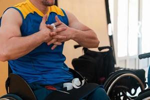 een gehandicapt basketbal speler zet Aan een korset en verbanden Aan zijn armen en vingers in voorbereiding voor een spel in de arena foto