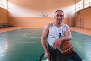 een portret van een glimlachen rolstoel basketbal speler zittend in een rolstoel aan het wachten voor de spel naar beginnen foto