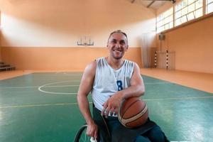 een portret van een glimlachen rolstoel basketbal speler zittend in een rolstoel aan het wachten voor de spel naar beginnen foto