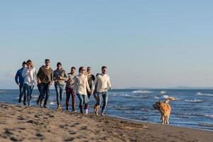 groep van vrienden rennen Aan strand gedurende herfst dag foto