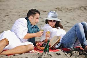 jong paar genieten van picknick Aan de strand foto