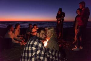 paar genieten van met vrienden Bij zonsondergang Aan de strand foto