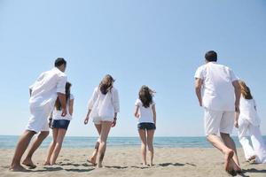 gelukkig mensen groep hebben pret en rennen Aan strand foto