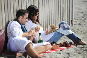 jong paar genieten van picknick Aan de strand foto