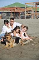 gelukkig familie spelen met hond Aan strand foto