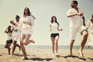 gelukkig mensen groep hebben pret en rennen Aan strand foto