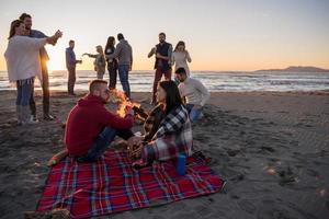 paar genieten van met vrienden Bij zonsondergang Aan de strand foto