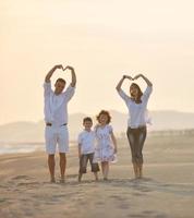 gelukkig jong familie hebben pret Aan strand Bij zonsondergang foto