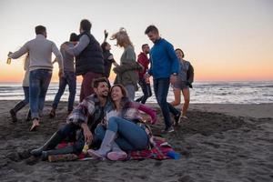 paar genieten van met vrienden Bij zonsondergang Aan de strand foto