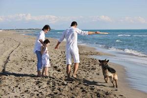 gelukkig familie spelen met hond Aan strand foto