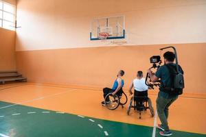 een cameraman met professioneel uitrusting records een bij elkaar passen van de nationaal team in een rolstoel spelen een bij elkaar passen in de arena foto