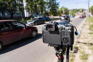 modern zwart professioneel spiegelloos camera Aan statief of monopod het schieten stad auto verkeer Bij zomer dag foto