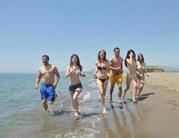 gelukkig mensen groep hebben pret en rennen Aan strand foto