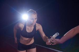 atletisch hardlopers voorbijgaan stok in relais ras foto