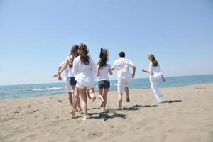 gelukkig mensen groep hebben pret en rennen Aan strand foto