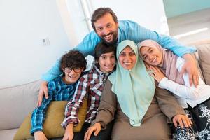 portret foto van een Arabisch moslim familie zittend Aan een bankstel in de leven kamer van een groot modern huis. selectief focus