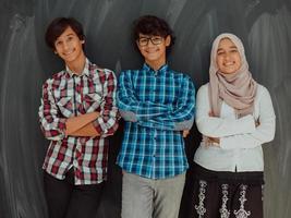 een portret van een groep van Arabisch tieners met gekruiste armen staand in voorkant van een school- bord . de concept van modern en geslaagd onderwijs foto