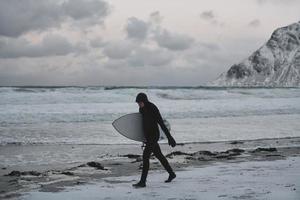 arctisch surfer gaan door strand na surfing foto