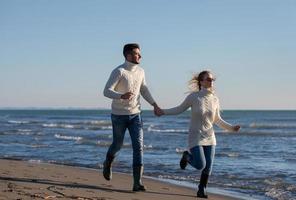 liefhebbend jong paar Aan een strand Bij herfst zonnig dag foto