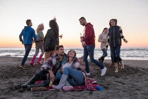 paar genieten van met vrienden Bij zonsondergang Aan de strand foto