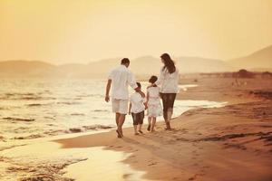 gelukkig jong familie hebben pret Aan strand Bij zonsondergang foto