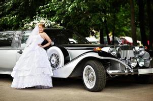 luxe bruid in een trouwjurk over retro limousine
