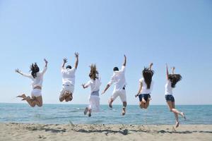 gelukkig mensen groep hebben pret en rennen Aan strand foto