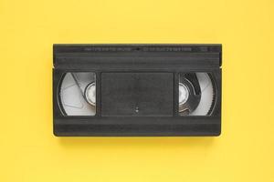 zwart vhs videoband opnemer cassette Aan geel achtergrond. oud verouderd technologie voor plakband opname en aan het kijken media films. retro, vintage, geschiedenis, nostalgie concept. top visie, vlak leggen foto