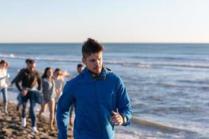 groep van vrienden rennen Aan strand gedurende herfst dag foto