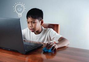onderwijs concept afbeelding. creatief idee en innovatie. jongen zittend staren Bij computer en Daar is een licht lamp icoon De volgende naar het. foto