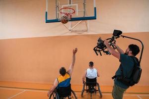 een cameraman met professioneel uitrusting records een bij elkaar passen van de nationaal team in een rolstoel spelen een bij elkaar passen in de arena foto