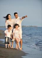 gelukkig jong familie hebben pret Aan strand Bij zonsondergang foto