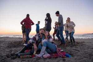 paar genieten van met vrienden Bij zonsondergang Aan de strand foto