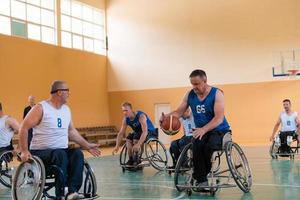 gehandicapt oorlog veteranen gemengd ras tegengesteld basketbal teams in rolstoelen gefotografeerd in actie terwijl spelen een belangrijk bij elkaar passen in een modern hal. foto
