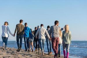 groep van vrienden rennen Aan strand gedurende herfst dag foto