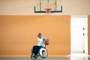 een oorlog ongeldig in een rolstoel treinen met een bal Bij een basketbal club in opleiding met professioneel sport- uitrusting voor de gehandicapt. de concept van sport voor mensen met handicaps foto
