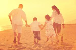 gelukkig jong familie hebben pret Aan strand Bij zonsondergang foto