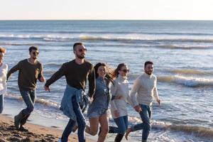 groep van vrienden rennen Aan strand gedurende herfst dag foto