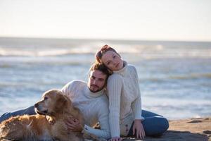 paar met hond genieten van tijd Aan strand foto