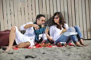 jong paar genieten van picknick Aan de strand foto